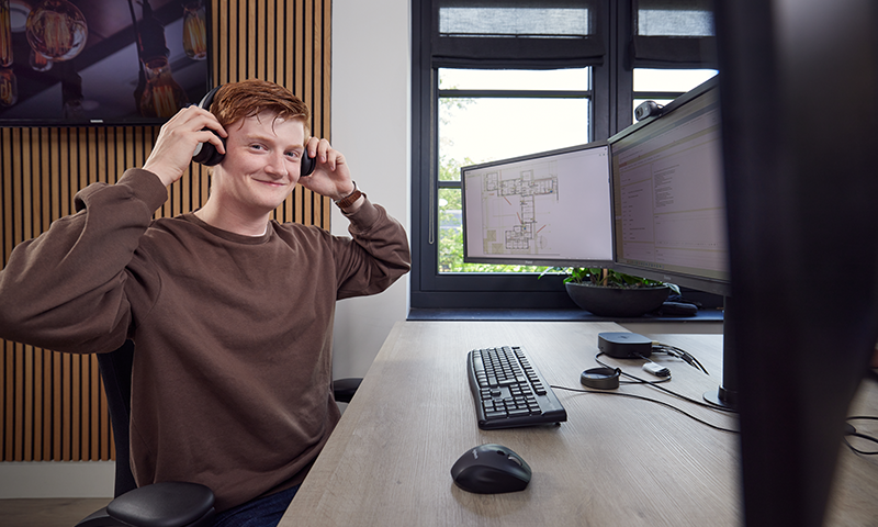 Wentzo collega zet koptelefoon op terwijl hij lachend in de camera kijkt
