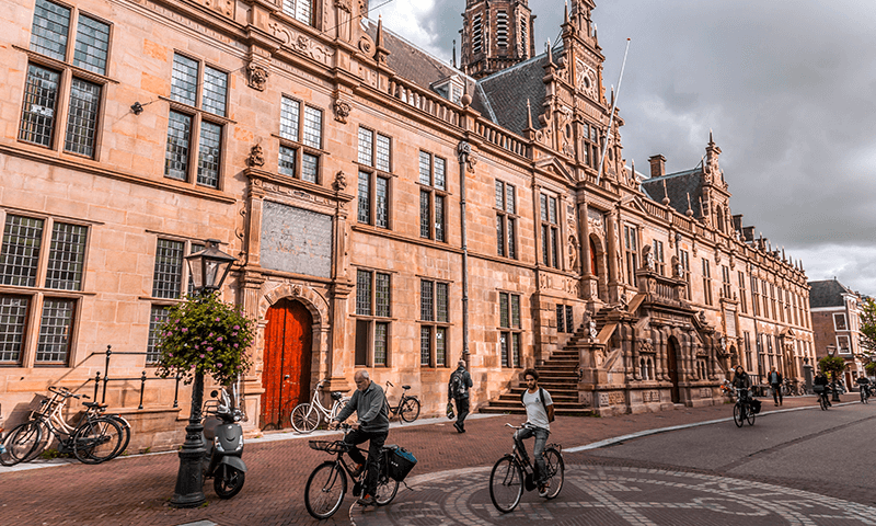 Gemeentehuis gemeente Leiden met fietsers die er voorbij fietsen.