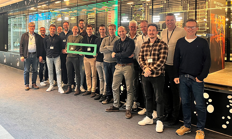 16 mannen staan als groep bij elkaar en kijken lachend de camera in. Ze houden een logo vast van Hewlett Packard Enterprise.