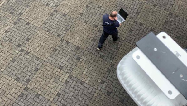 Wentzo collega loopt over een parkeerplaats met zijn laptop