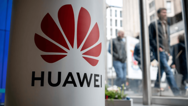 Een witte paal waarop het Huawei logo zichtbaar is. Op de achtergrond lopen mensen over straat.