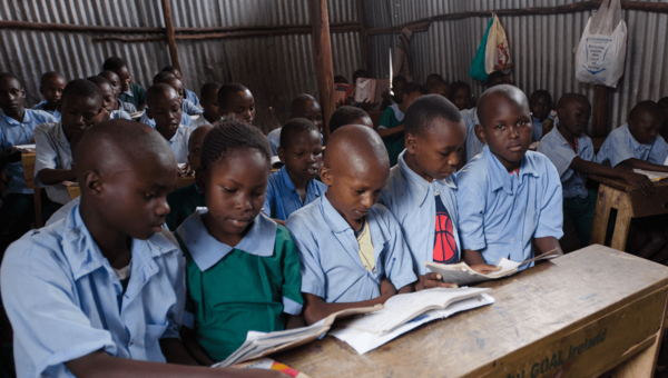Kinderen in Kenya volgen een les op school. Ze kijken naar boekjes die ze vasthouden.