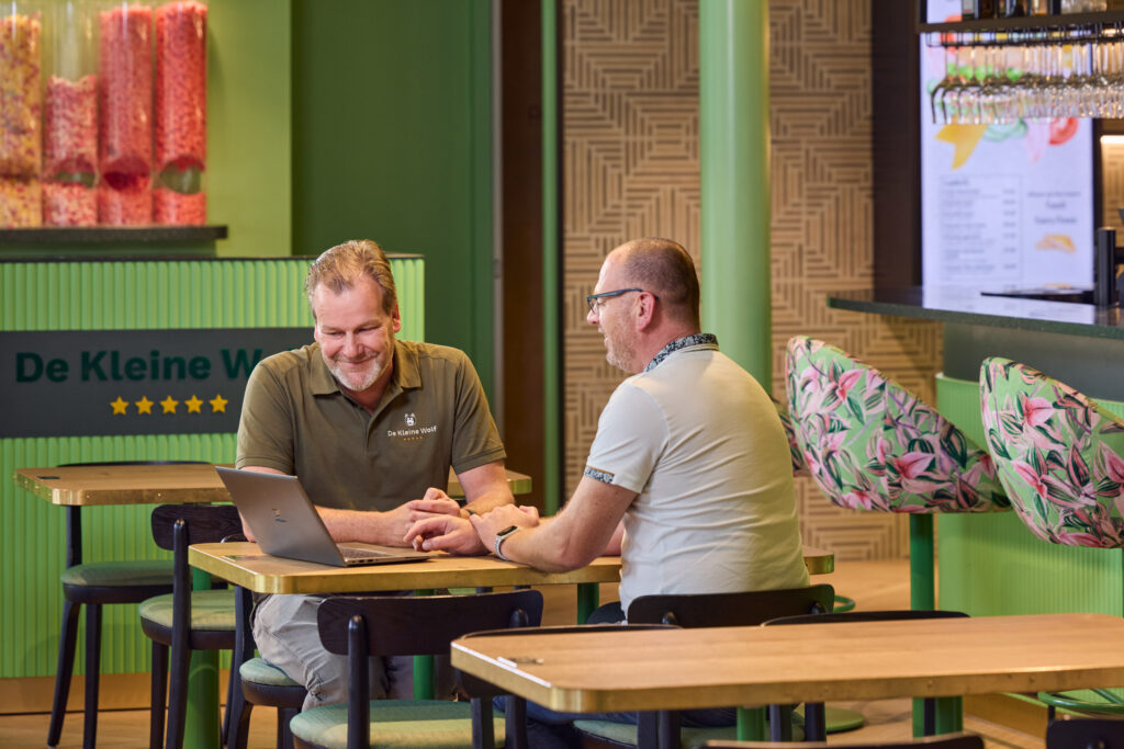 Een Wentzo collega zit aan een tafel en kijkt samen met de technisch manager van de Kleine Wolf naar een laptop