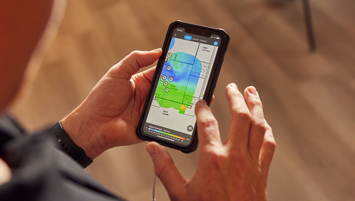 Mobiele telefoon wordt vastgehouden waarop Wentzo Site Survey plattegrond zichtbaar is